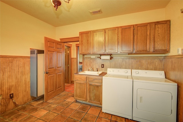 washroom featuring cabinets, wooden walls, separate washer and dryer, and sink