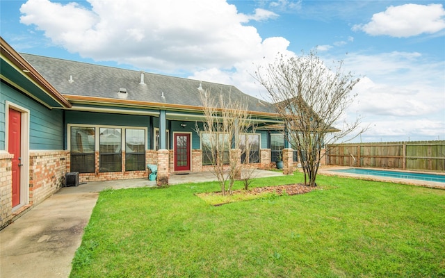 rear view of property featuring a yard, a fenced in pool, and a patio area