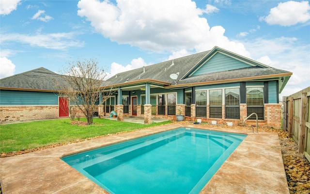 rear view of property with a fenced in pool, a lawn, and a patio area