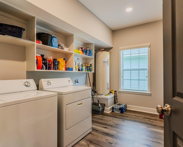 clothes washing area with washing machine and dryer, electric water heater, and hardwood / wood-style floors