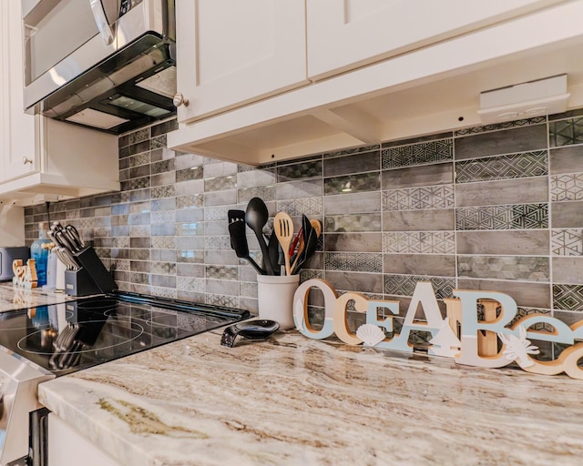 kitchen featuring stainless steel appliances, light stone countertops, decorative backsplash, and white cabinets