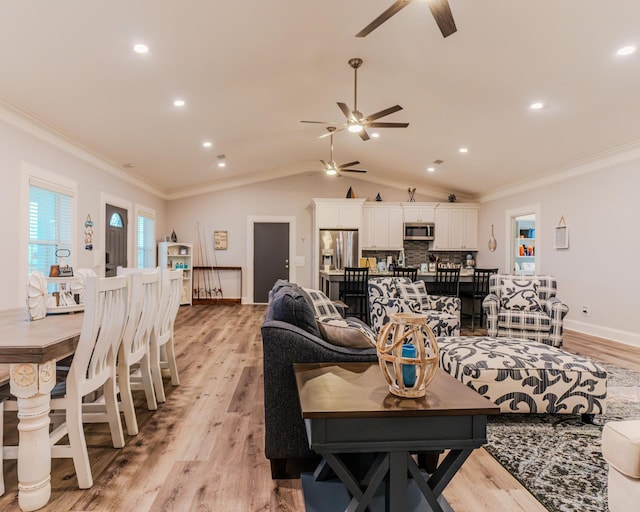 living room featuring ornamental molding, lofted ceiling, and light hardwood / wood-style floors