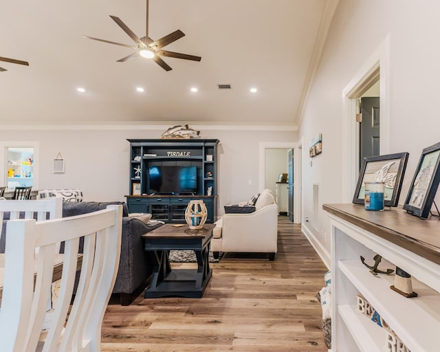 living room featuring wood-type flooring, crown molding, and ceiling fan