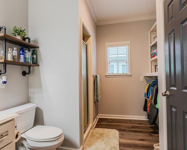 bathroom with hardwood / wood-style floors, ornamental molding, vanity, toilet, and a shower with door