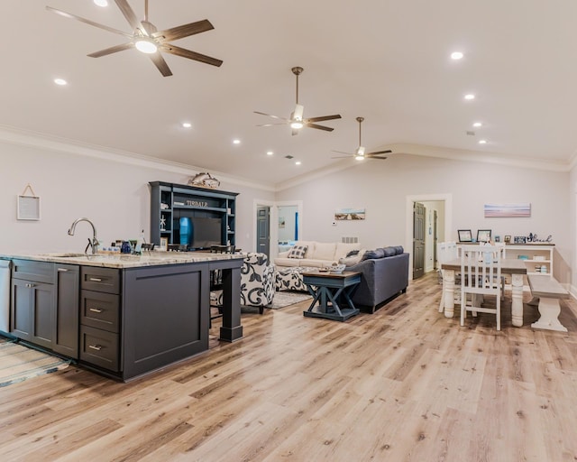 kitchen featuring crown molding, sink, a center island with sink, and light hardwood / wood-style floors