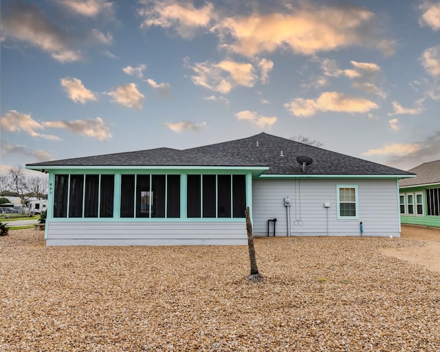 back house at dusk featuring a sunroom