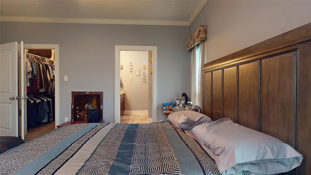 bedroom with a walk in closet, ornamental molding, connected bathroom, and a closet