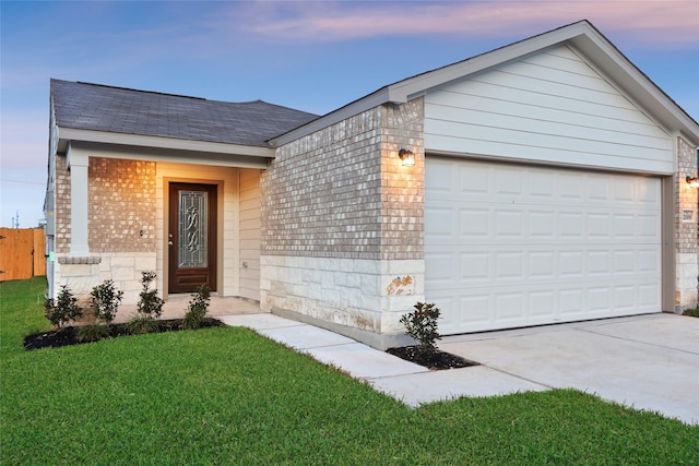 single story home featuring a garage and a lawn