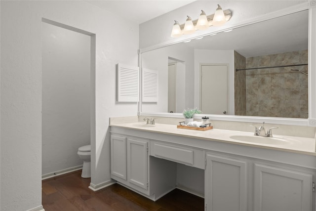 bathroom featuring vanity, toilet, hardwood / wood-style floors, and a tile shower