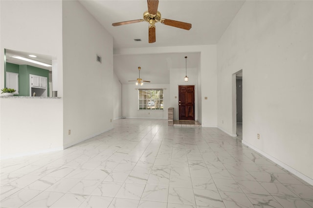 unfurnished living room with ceiling fan and a high ceiling