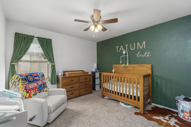 carpeted bedroom with a nursery area and ceiling fan