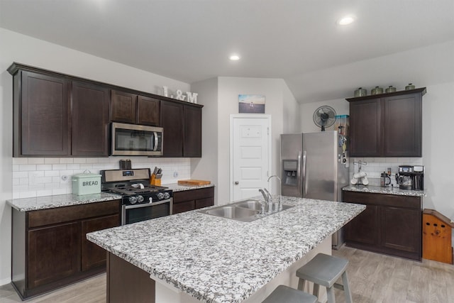 kitchen featuring appliances with stainless steel finishes, sink, a kitchen island with sink, and light hardwood / wood-style floors