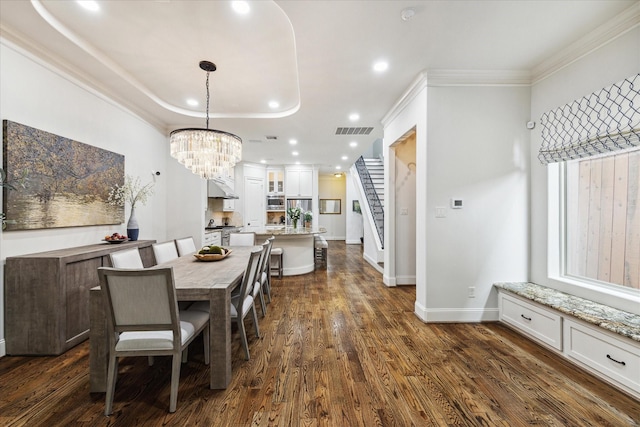 dining room with a notable chandelier, crown molding, dark wood-type flooring, and a raised ceiling