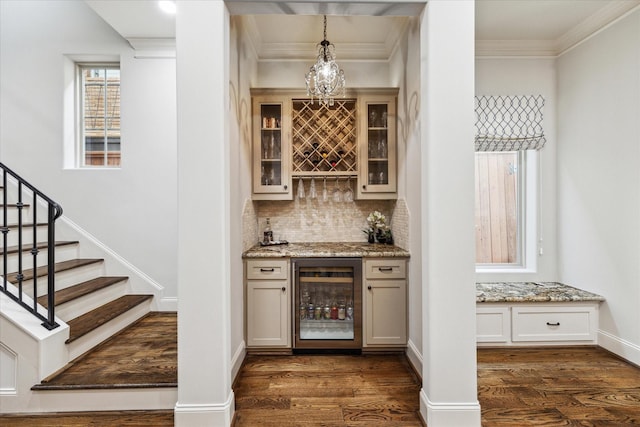 bar with dark hardwood / wood-style floors, pendant lighting, beverage cooler, ornamental molding, and light stone counters