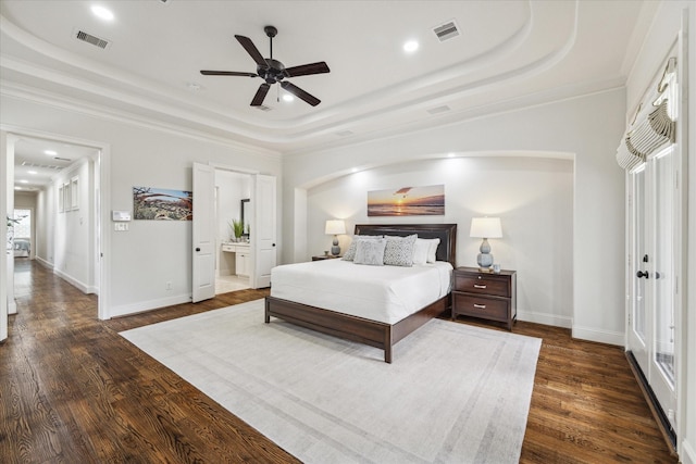 bedroom with dark wood-type flooring, ensuite bathroom, crown molding, and a raised ceiling