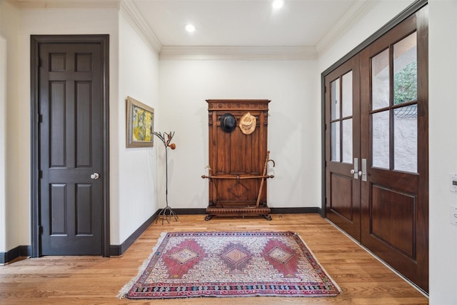 foyer with ornamental molding and light hardwood / wood-style floors