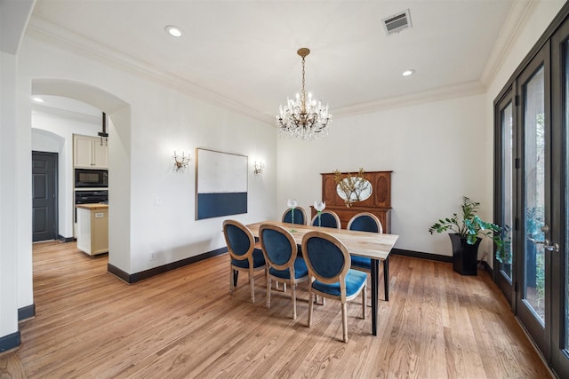 dining area featuring ornamental molding, a healthy amount of sunlight, a chandelier, and light hardwood / wood-style flooring