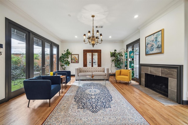 living room featuring a fireplace, ornamental molding, french doors, and light wood-type flooring