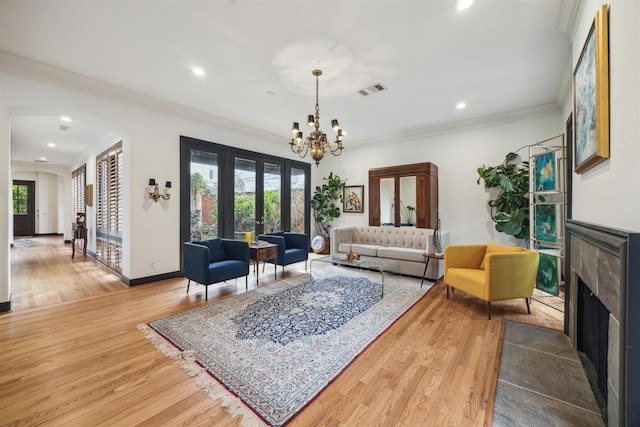 living room featuring a healthy amount of sunlight, a high end fireplace, wood-type flooring, and ornamental molding