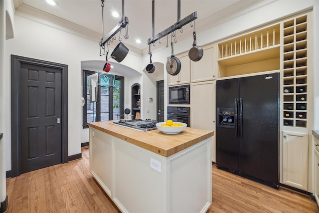 kitchen featuring butcher block countertops, white cabinetry, ornamental molding, a kitchen island, and black appliances