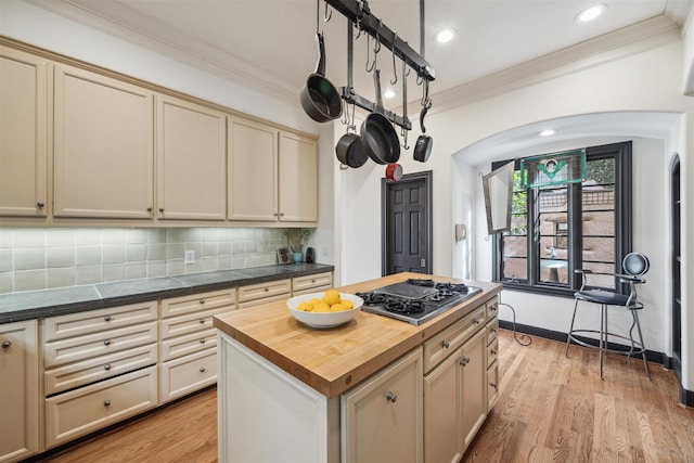 kitchen featuring butcher block counters, tasteful backsplash, a kitchen island, cream cabinetry, and stainless steel gas stovetop