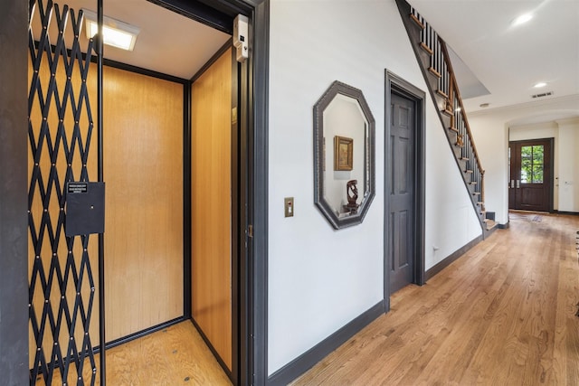 corridor with crown molding, light hardwood / wood-style flooring, and elevator