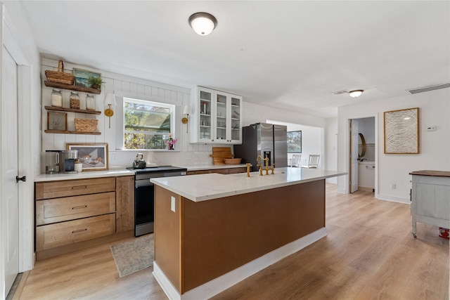 kitchen with a center island with sink, visible vents, light wood-style flooring, glass insert cabinets, and stainless steel refrigerator with ice dispenser