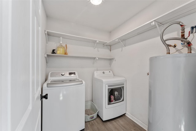 laundry room with light wood-type flooring, laundry area, washing machine and dryer, and water heater