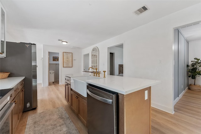 kitchen featuring a sink, visible vents, light countertops, appliances with stainless steel finishes, and light wood finished floors