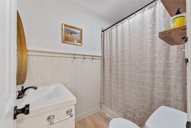 full bath featuring a wainscoted wall, wood finished floors, toilet, and a shower with curtain