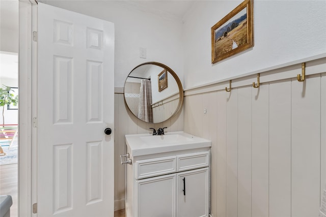 full bath featuring a wainscoted wall and vanity