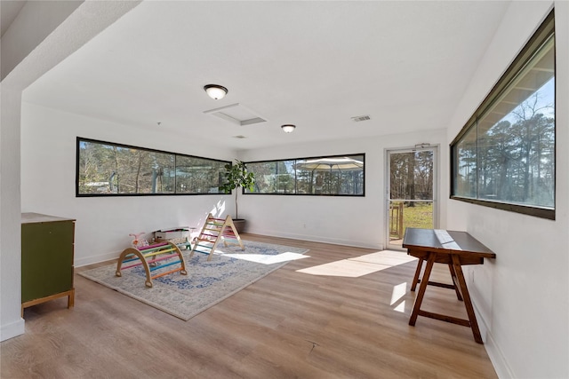 game room featuring baseboards, wood finished floors, and a healthy amount of sunlight