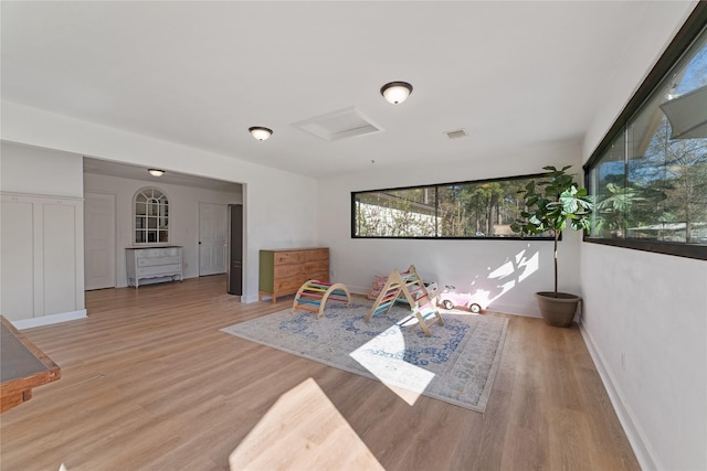 recreation room featuring visible vents, wood finished floors, attic access, and baseboards