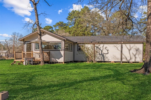 rear view of house featuring a deck, a yard, and roof with shingles