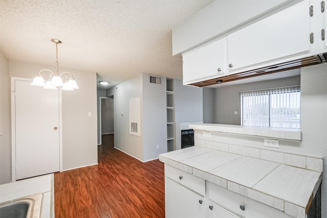 kitchen featuring decorative light fixtures, a textured ceiling, tile counters, dark hardwood / wood-style floors, and white cabinets