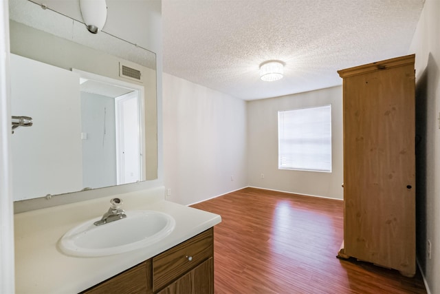 bathroom with wood-type flooring, vanity, and a textured ceiling