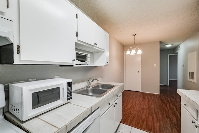 kitchen with sink, white cabinets, hanging light fixtures, tile counters, and white appliances