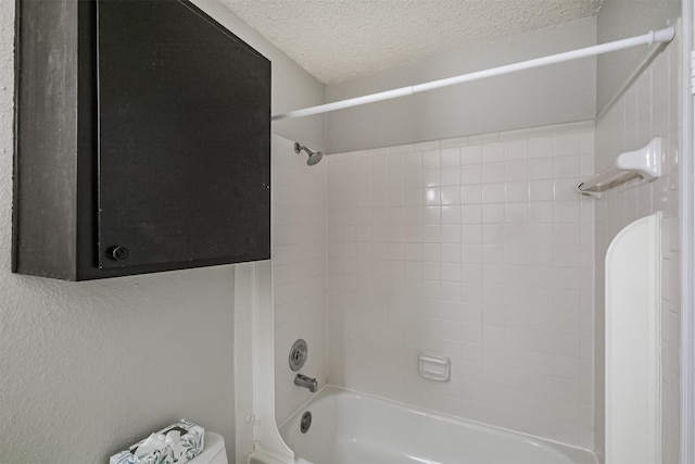 bathroom with toilet, tiled shower / bath combo, and a textured ceiling