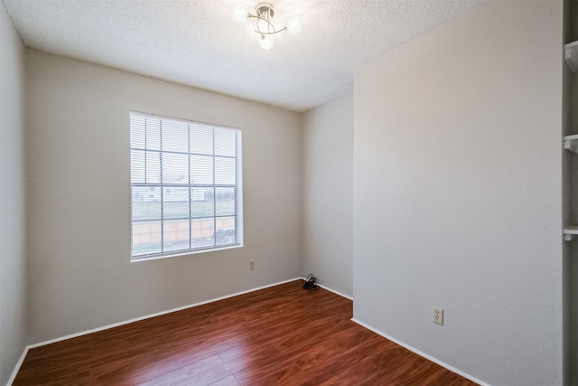 spare room with dark wood-type flooring and a textured ceiling