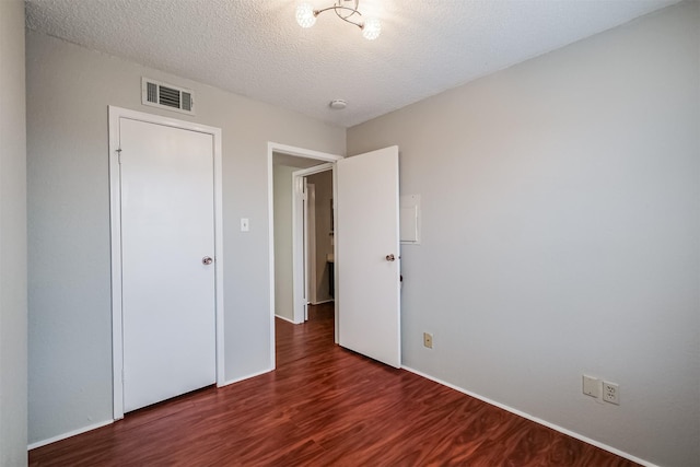 unfurnished bedroom featuring dark hardwood / wood-style floors and a textured ceiling