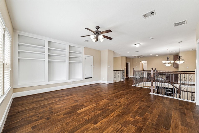 unfurnished room with dark wood-type flooring, ceiling fan with notable chandelier, and a wealth of natural light