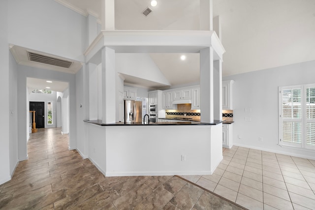 kitchen featuring tasteful backsplash, stainless steel fridge, white cabinets, and kitchen peninsula