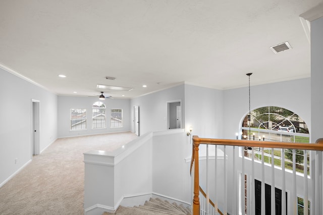 hall featuring light carpet, ornamental molding, and an inviting chandelier