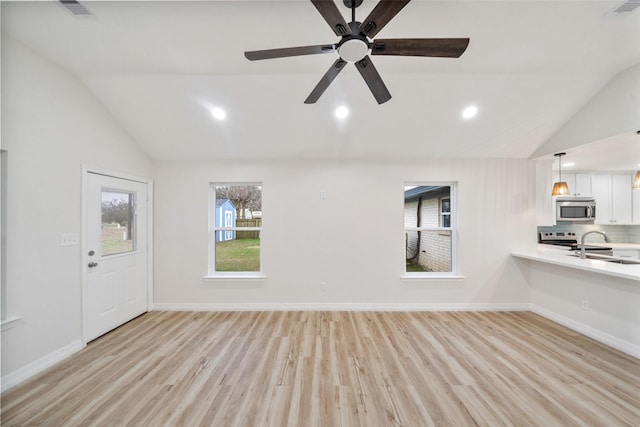 unfurnished living room featuring vaulted ceiling, sink, and light wood-type flooring