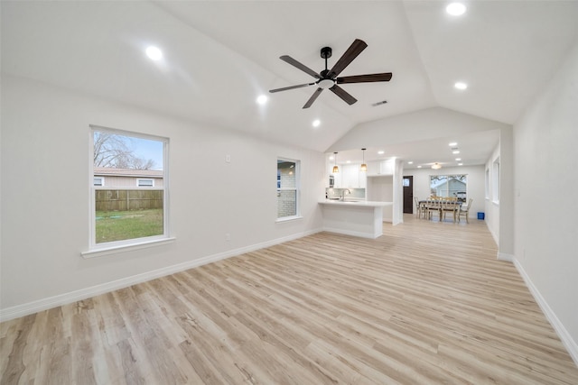 unfurnished living room with ceiling fan, lofted ceiling, sink, and light hardwood / wood-style floors