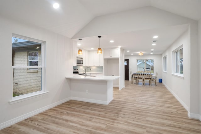 kitchen with sink, white cabinetry, hanging light fixtures, kitchen peninsula, and stainless steel appliances