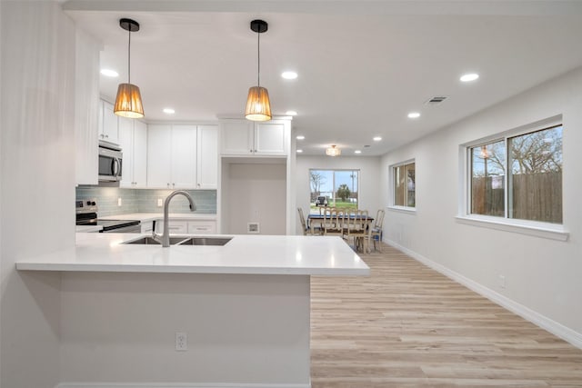 kitchen featuring stainless steel appliances, decorative light fixtures, sink, and white cabinets