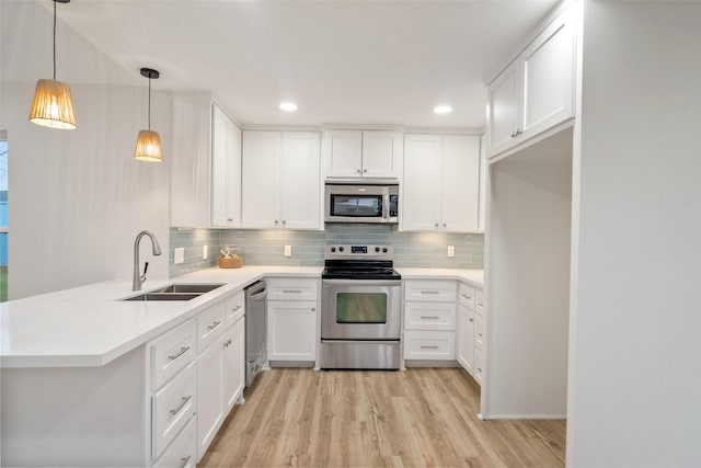kitchen featuring stainless steel appliances, kitchen peninsula, sink, and white cabinets