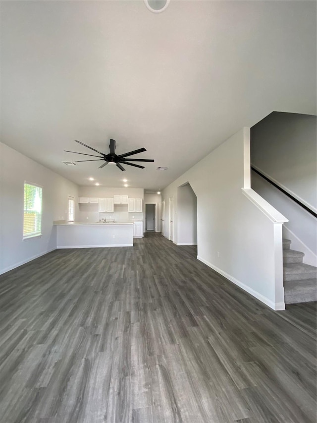 unfurnished living room featuring dark hardwood / wood-style floors and ceiling fan