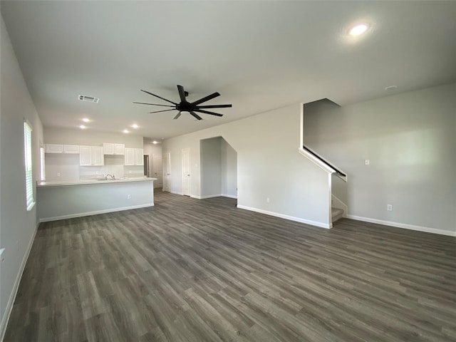 unfurnished living room with dark wood-type flooring, ceiling fan, and sink